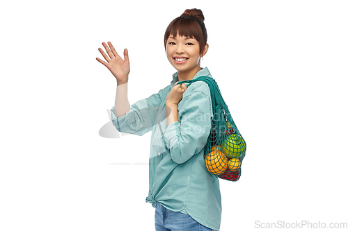 Image of happy asian woman with food in reusable string bag