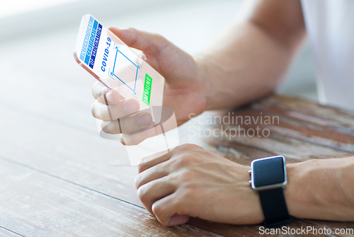 Image of hand with certificate of vaccination on smartphone