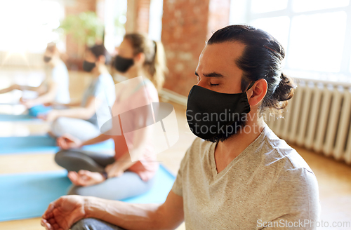 Image of group of people in masks doing yoga at studio