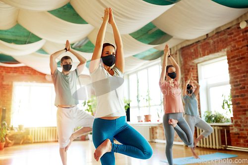 Image of group of people in masks doing yoga at studio