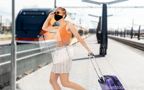 Image of woman in mask with travel bag over train