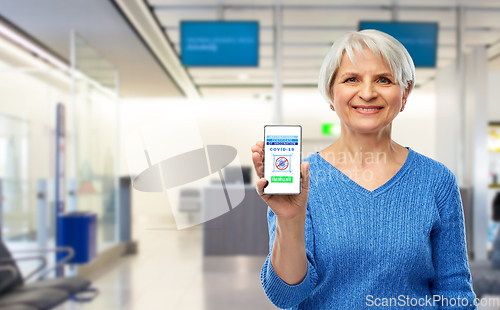 Image of old woman with certificate of vaccination on phone