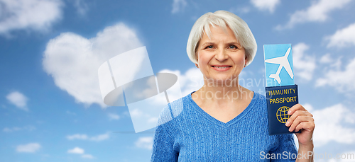 Image of senior woman with immunity passport and air ticket