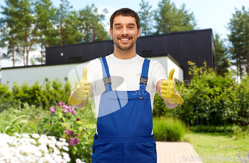 Image of happy male worker or cleaner in gloves at garden