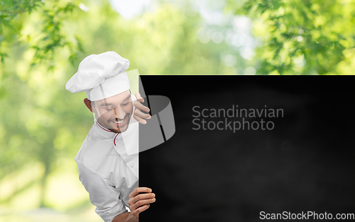 Image of happy smiling male chef with big black chalkboard