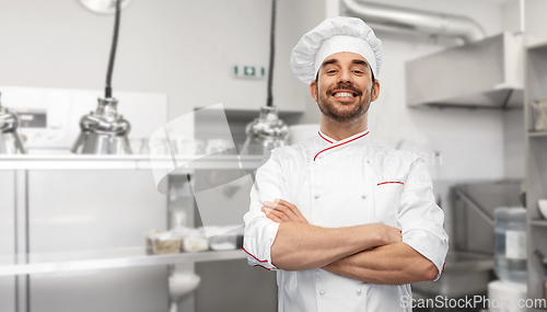 Image of happy smiling male chef in toque at kitchen