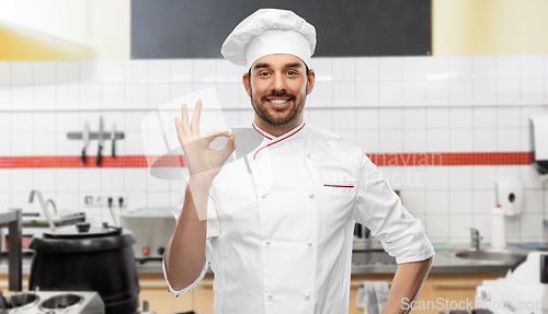 Image of happy smiling male chef showing ok at kitchen