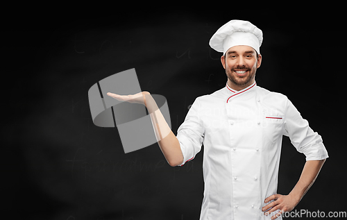 Image of happy smiling male chef holding something on hand