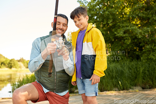 Image of happy smiling father and son fishing on river