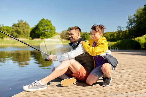 Image of happy smiling father and son fishing on river