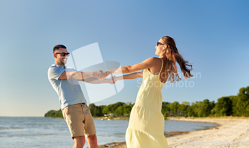 Image of happy couple holding hands on summer beach