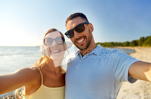 Image of happy couple taking selfie on summer beach