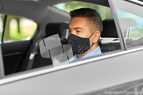 Image of man or male passenger wearing black mask in car