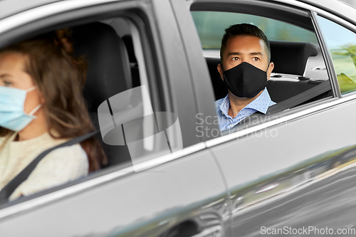 Image of female driver in mask driving car with passenger