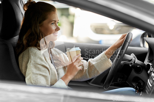 Image of woman or female driver with coffee driving car