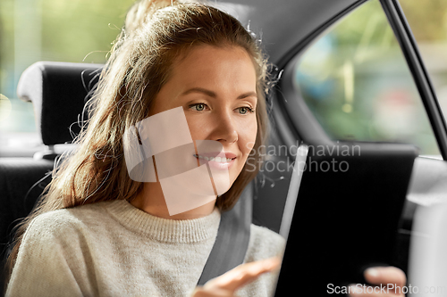Image of smiling woman in car using tablet pc computer