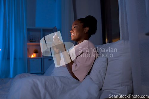 Image of woman with smartphone in bed at home at night