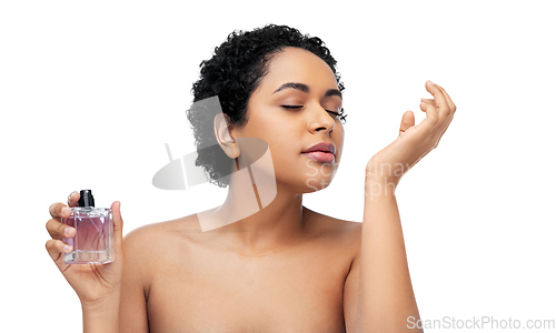 Image of young african american woman smelling perfume