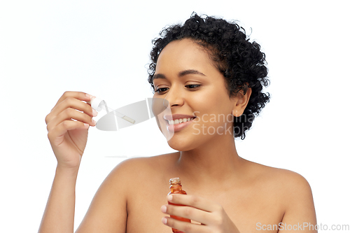 Image of happy african american woman with bottle of serum