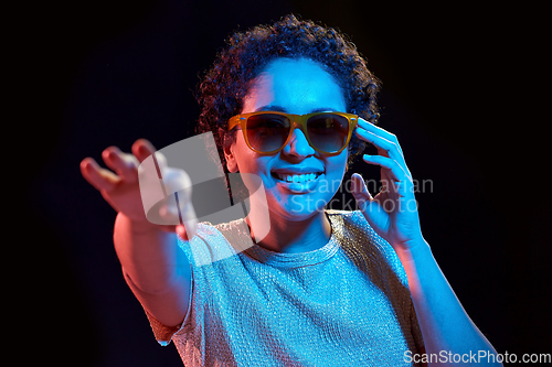 Image of african woman in sunglasses over neon lights