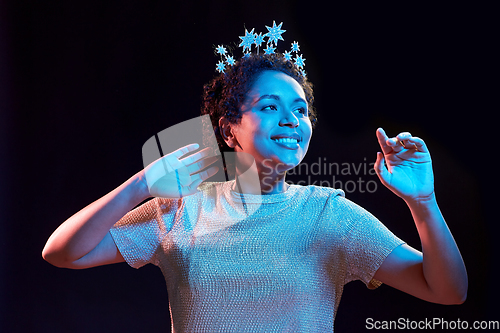 Image of african woman in party cap with blower over black