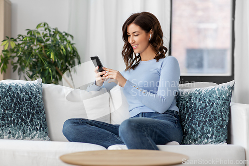 Image of woman with earphones and smartphone at home