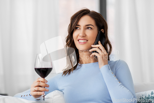 Image of woman calling on smartphone and drinking red wine