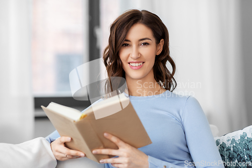 Image of young woman reading book at home