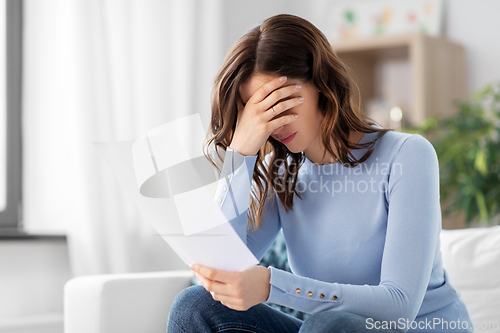 Image of stressed woman with paper sheet at home