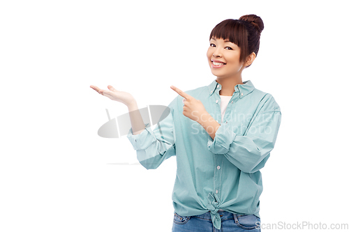 Image of happy asian woman holding something on hand