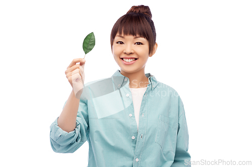 Image of smiling asian woman holding green leaf