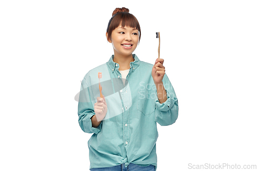 Image of asian woman with wooden and plastic toothbrushes