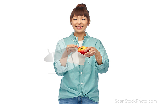 Image of happy woman putting apple into reusable bag