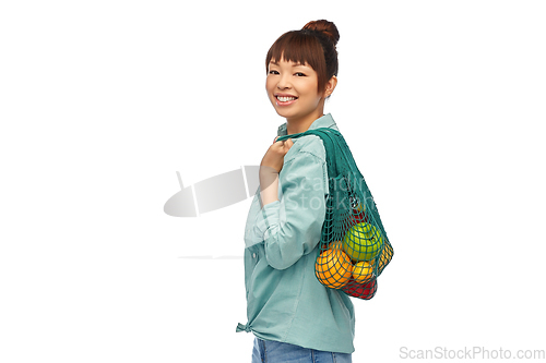 Image of happy asian woman with food in reusable string bag