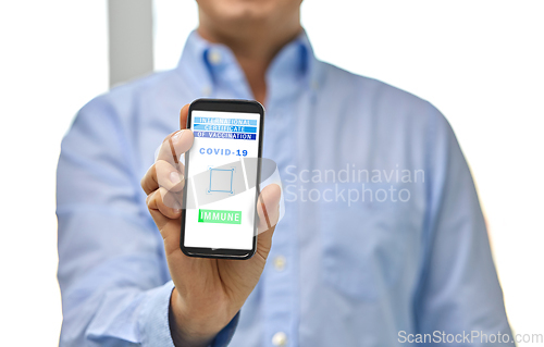 Image of hand with virtual immunity passport on smartphone