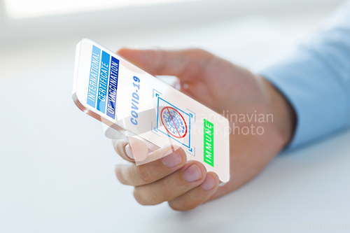 Image of hand with certificate of vaccination on smartphone