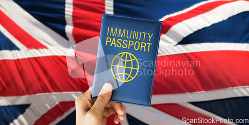 Image of hand holding immunity passport over british flag