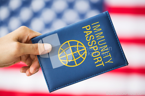 Image of hand holding immunity passport over american flag