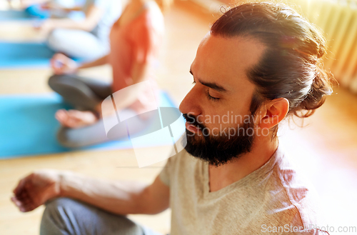 Image of man with group of people meditating at yoga studio