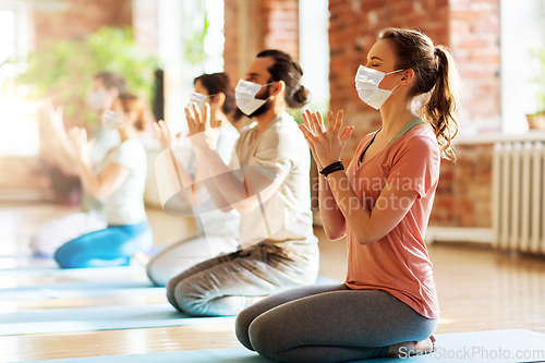 Image of group of people in masks meditating at yoga studio