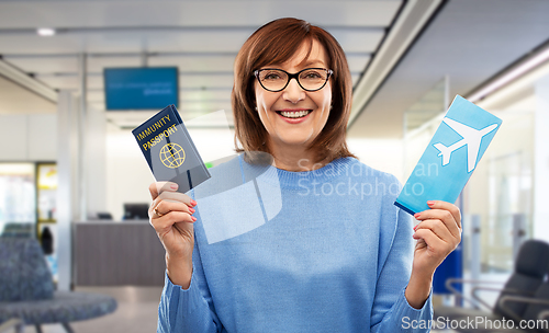 Image of senior woman with immunity passport and air ticket