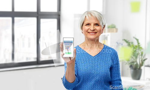 Image of old woman with certificate of vaccination on phone