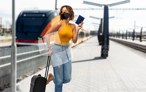 Image of woman in mask with travel bag over train
