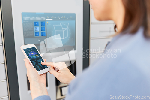 Image of woman with smartphone at automated parcel machine