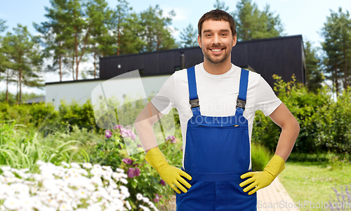 Image of happy male worker or cleaner in gloves at garden