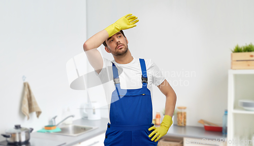 Image of tired male worker or cleaner in gloves at kitchen