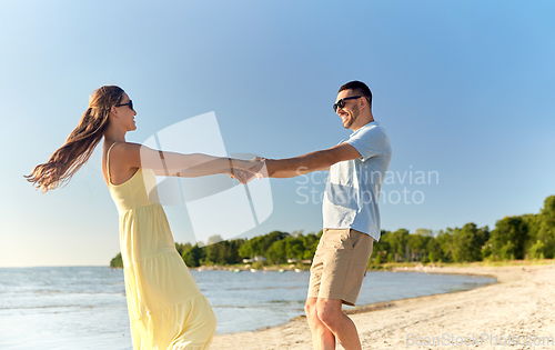 Image of happy couple holding hands on summer beach