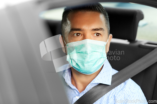 Image of man or male passenger wearing mask in car