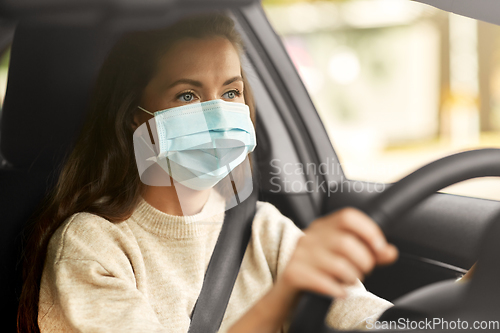 Image of woman or female driver in mask driving car in city