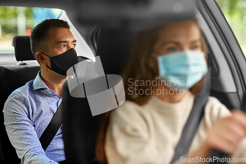 Image of female driver in mask driving car with passenger